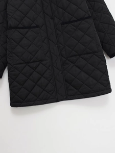 Detail der schwarzen Steppjacke mit großen Taschen und Metall-Druckknöpfen am Saum
