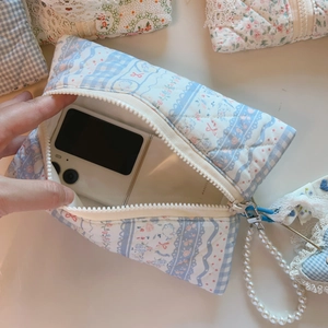 Detailed interior of blue floral quilted cotton makeup bag holding a foldable smartphone