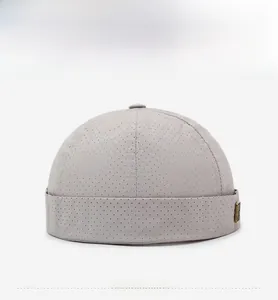 Détail du bonnet docker gris clair en maille avec trous respirants et plaque logo