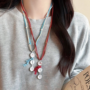Détail du collier avec pendentif bonhomme de neige et écharpe en tricot sur velours