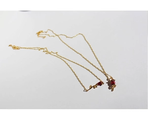 Close-up of golden brass necklaces with handcrafted red enamel rose flower pendants