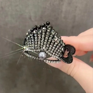 Detail of a crown hair claw clip with black crystals and a central pearl accent