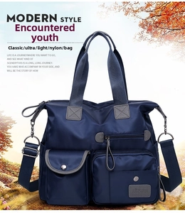 Front detail of large blue nylon travel bag with dual handles and detachable shoulder strap