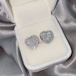 Macro shot of silver heart earrings with sparkling diamonds in a white gift box