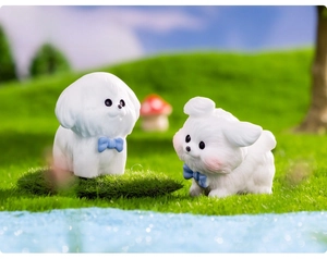 Close-up of cute white puppy resin figurines with blue bows on artificial moss garden