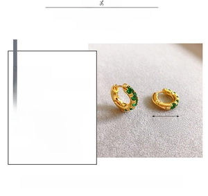 Detail showing 18K gold-plated earrings with green zircon insets and 1.75cm diameter