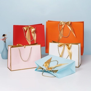 Colorful paper gift bags with golden ribbon bows and braided handles for premium shopping