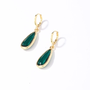 Detailed close-up of gold earrings featuring green teardrop gemstones on white background