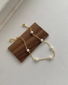 Macro shot of s925 silver gold-plated bracelet with six pearls on walnut wood display