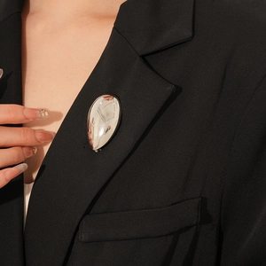 Nahaufnahme der polierten silbernen Tropfenbrosche auf einem schwarzen Blazer-Revers