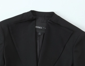 Détail du col d'un blazer noir avec étiquette de marque et texture de tissu sergé
