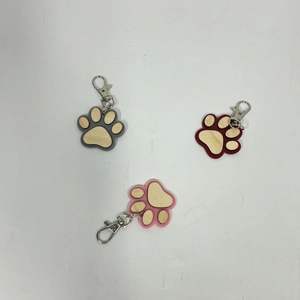 Detailed view of paw-shaped wooden keychains in grey, reddish-brown, and pink wood