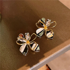 Elegant two-tone gold and silver flower petal earrings on a dark textured surface
