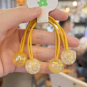Detail of handmade yellow hair tie featuring glittery beads and transparent spheres