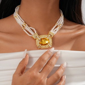 Close-up of elegant multi-layer pearl necklace with a vintage gold square gem pendant