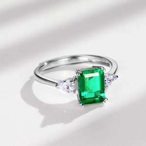 Elegant silver three-stone ring featuring emerald-cut green stone and pear-cut side gems
