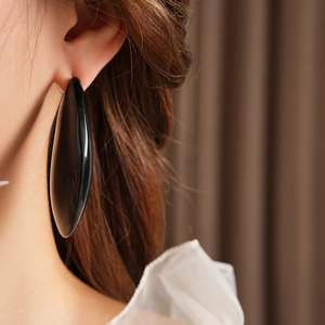 Gros plan d'une grande boucle d'oreille goutte en résine noire portée par un mannequin