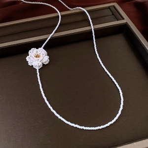 Detailed view of woven camellia pearl necklace with golden center on velvet display
