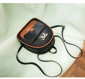 Close-up of a stylish two-tone small backpack featuring a golden bow metal accessory