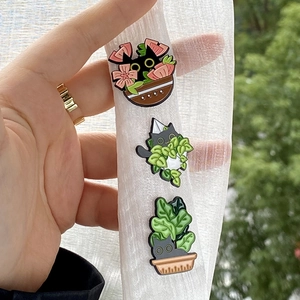 Three creative black cat enamel pins with plants and flower pots in hand display