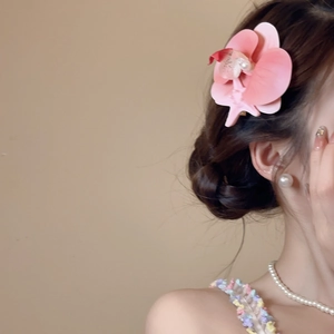 Detailed view of a pink orchid hair clip with gradient petals and pearl on a model's hair