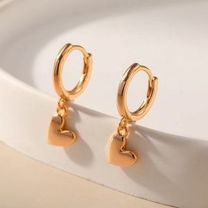Close-up of golden heart pendant earrings with high-polished finish on stone stand
