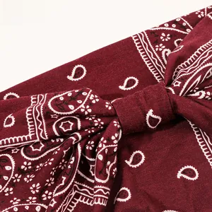 Detail of burgundy paisley print headband with a knotted bow design and soft fabric texture