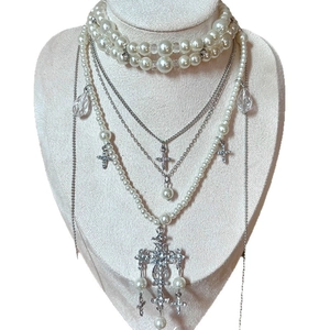 Layered baroque pearl necklace featuring silver cross pendants and crystal accents