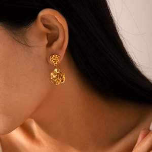 Detailed view of 18K gold rose flower earrings with textured metallic petals on model