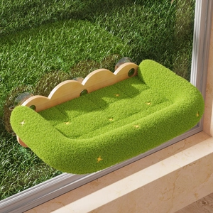 Green plush cat window perch with wooden frame and suction cups, showing a meadow view