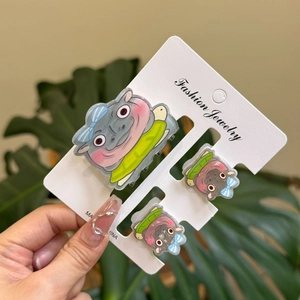 Set of three acrylic hippo hair clips with blue bows displayed on a white jewelry card