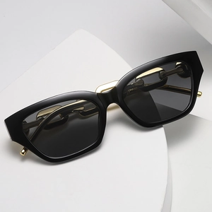 Fashion cat-eye sunglasses with black frame and golden metal chain temples on white props