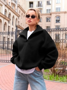 Oversized black half-zip sweatshirt with a high collar in a minimalist street style