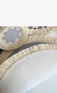 Detail of round woven cotton placemat with purple geometric print and soft fringe
