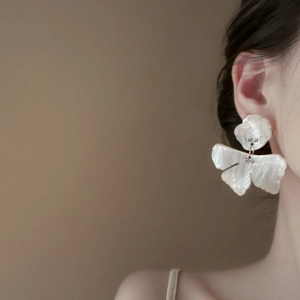 Close-up of pearl white resin flower earrings with sparkling rhinestone center detail
