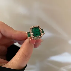 Close-up of vintage emerald green rectangular ring with diamonds in rose gold finish