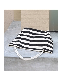 Close-up of a striped canvas tote bag with textured fabric and white woven handles