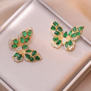 Detailed view of butterfly earrings with green zircon stones on gold metal finish
