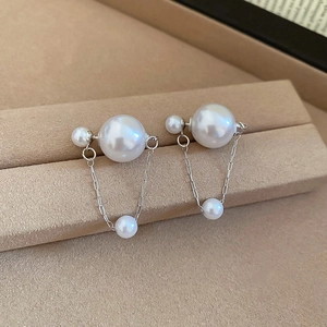 Macro shot of silver pearl drop earrings with U-shaped chain design on velvet