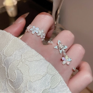 Détail de bagues fleurs en perles et zircon bleu clair et rose sur la main du modèle