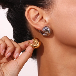 Detailed view of polished water-drop earrings in gold and silver finish on a model