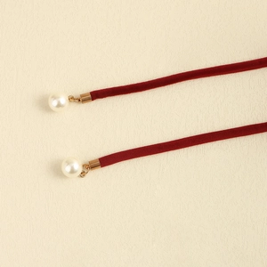 Close-up of burgundy velvet belt cord with white pearl tassels and gold accents