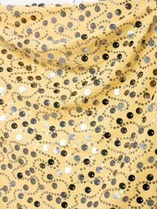 Macro detail of yellow fabric with sparkling black and silver sequins in a wavy pattern