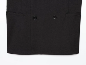 Detail shot of black vest fabric showing two resin buttons and symmetrical welt pockets