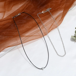 Close-up of minimalist silver heart pendant with black cord and sleek link chain