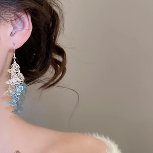 Gros plan sur les boucles d'oreilles papillon argentées avec dégradé bleu sur le mannequin