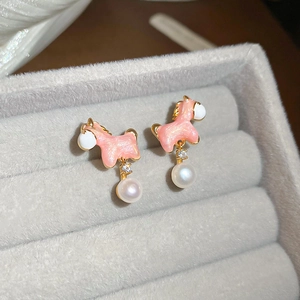 Macro shot of gold pony earrings with pink enamel and a round white pearl drop