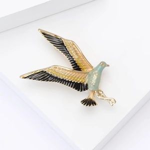 Macro detail of enamel hummingbird brooch featuring golden metal and colorful wings