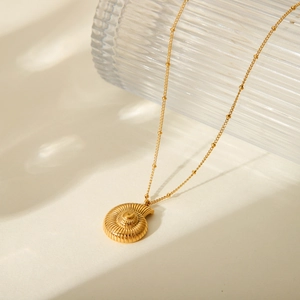 Macro detail of 18k gold plated stainless steel necklace with seashell conch pendant