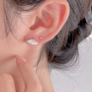 Macro view of minimalist 925 sterling silver shell stud earrings worn by a model